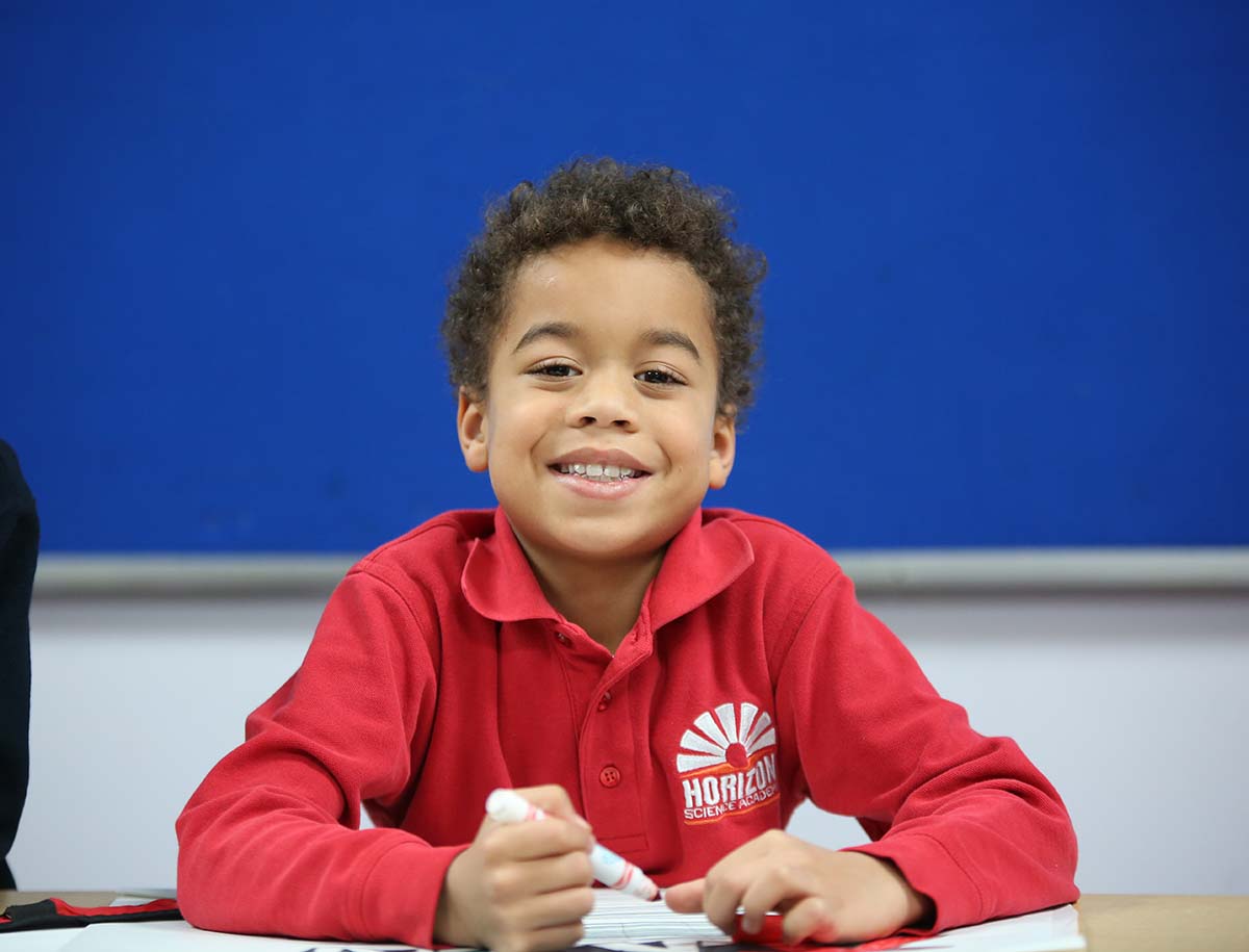 Elementary student smiling and posing together in a classroom.